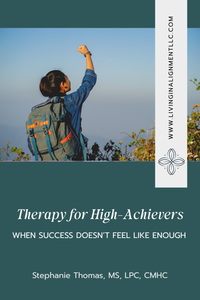 Woman raising her fist in triumph on a mountain trail at sunrise, symbolizing balanced success for high achievers